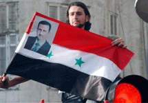 Сирийский флаг с портретом президента Ассада в руках демонстранта. Фото АР