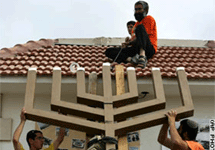 Жители Нецарим снимают семисвечник с крыши своей синагоги. Фото АР