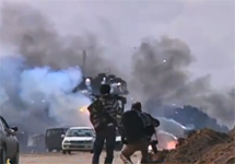 Ливийские повстанцы наблюдают за горящей техникой правительственных войск. Кадр "Аль-Джазиры"