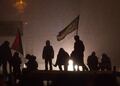 Вечер 21 января. Протестующие на крышах сгоревших автобусов в свете милицейского прожектора. Фото Юрия Тимофеева/Грани.Ру