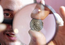 Брайан Малин рассматривает монету римского императора Домитиана, которую он обнаружил как часть клада с помощью металлоискателя на сельхозугодьях возле Оксфорда. Фото Guardian