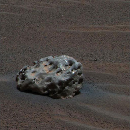 Железный метеорит на Марсе - первый метеорит подобного типа из всех, когда-либо обнаруженных на другой планете (достаточно крупных метеоритов не удалось найти даже на исхоженной американскими астронавтами и нашими "Луноходами" Луне). Изъеденный эрозией объект размером с баскетбольный мяч состоит главным образом из железа и никеля. Показания спектрометров вездехода Opportunity позволили уточнить его состав. Opportunity использовал свою панорамную камеру, чтобы получить это приблизительное цветное изображение в свой 339-й марсианский день (или золь) 6 января 2005 года. Фото NASA/JPL/Cornell с сайта www.space.com