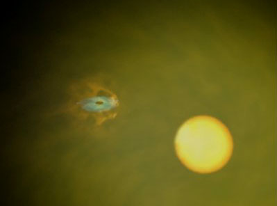 Так художник представляет себе скрытую систему двойной звезды. Массивная звезда-компаньон (справа) исторгает много газа в форме "звездного ветра". Компактная компонента - черная дыра с мощным гравитационным полем - поглощает этот газ, часть которого ускоряется до высоких скоростей в горячем диске, испуская большое количество энергии во всех спектральных диапазонах, от гамма-лучей до видимого и инфракрасного излучения. Однако остатки газа, окружающие черную дыру, формируют плотное облако, которое блокирует большую часть радиации. Только очень энергичные гамма-лучи могут избежать ловушки, они-то и обнаружены "Интегралом". Изображение с сайта www.esa.int
